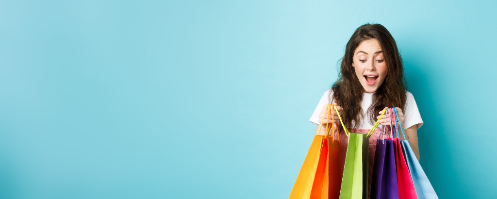Happy shopper carrying colorful shopping bags